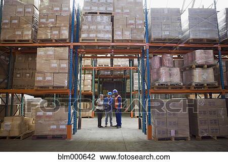 Stock Image - Workers talking in warehouse. Fotosearch