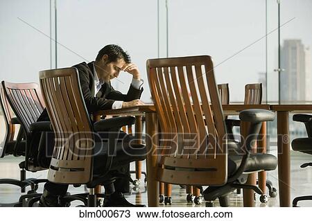 Stock Image - Worried businessman waiting in conference room for meeting. Fotosearch