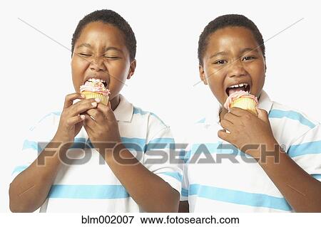 Young African twin brothers eating cupcakes View Large Photo Image Stock Photo - Young African twin brothers eating cupcakes. Fotosearch
