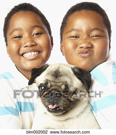 Stock Image - Young African twin brothers holding small dog. Fotosearch
