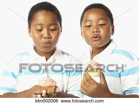 Young African twin brothers holding cupcakes with candles View Large Photo Image Stock Photograph - Young African twin brothers holding cupcakes with candles. Fotosearch