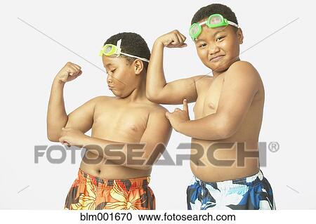 Stock Image - Young African twin brothers in bathing suits flexing. Fotosearch