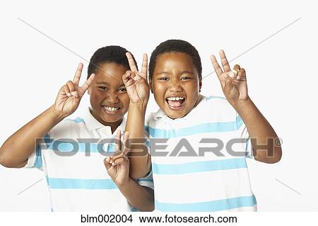 Picture - Young African twin brothers smiling and making peace sign. Fotosearch