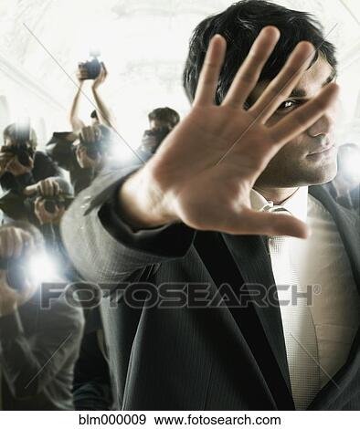 Young male celebrity shielding face from photographers View Large Photo Image Stock Photo - Young male celebrity shielding face from photographers. Fotosearch