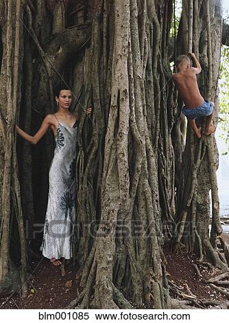 Young woman in evening gown and boy climbing tree View Large Photo Image Stock Photography - Young woman in evening gown and boy climbing tree. Fotosearch