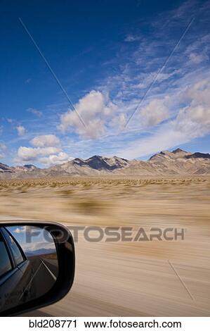 Stock Image - A car driving through the desert landscape. Fotosearch