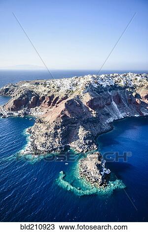 Stock Image - Aerial view of city built on rocky coastline, Oia, Egeo, Greece. Fotosearch
