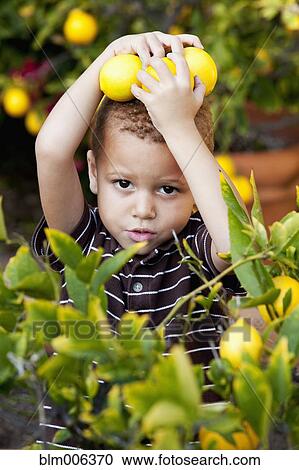 Stock Image - African American boy holding lemons. Fotosearch
