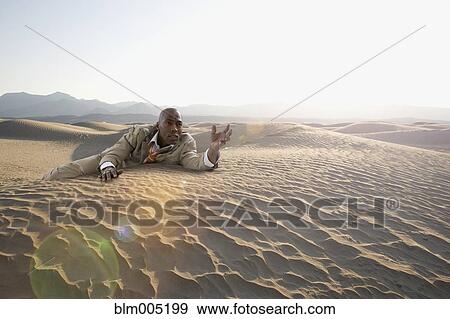 Stock Photo - African American businessman crawling in desert. Fotosearch