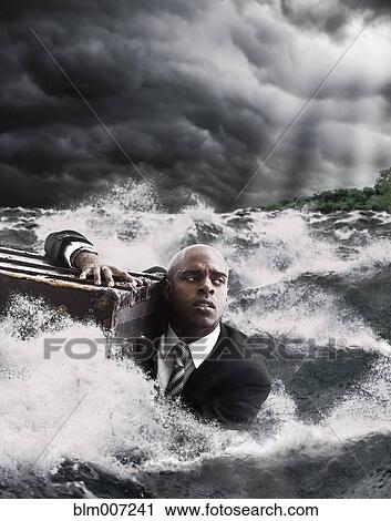 Stock Image - African American businessman in ocean holding trunk. Fotosearch