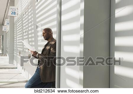 Picture - African American businessman reading papers in office. Fotosearch