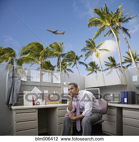 Stock Image - African American businessman daydreaming of vacation at desk. Fotosearch