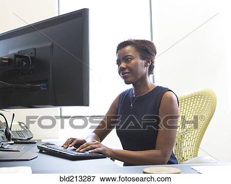 Stock Photo - African American businesswoman working at desk. Fotosearch
