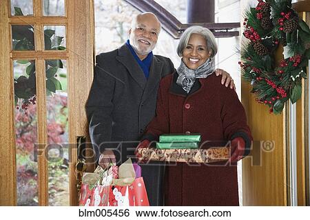 Stock Photograph - African American couple arriving with Christmas gifts. Fotosearch