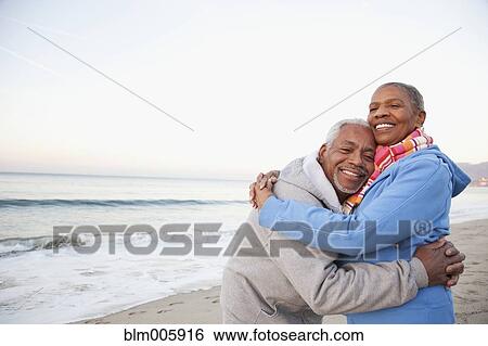 Stock Photograph - African American couple hugging on beach. Fotosearch