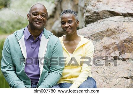 Stock Image - African American couple sitting in park. Fotosearch