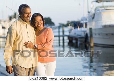 Stock Image - African American couple smiling at pier. Fotosearch