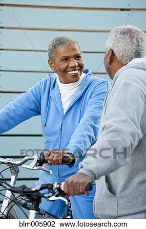Stock Image - African American couple standing with bicycles. Fotosearch
