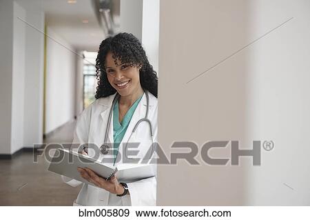 Stock Photo - African American doctor with medical chart in hospital hallway. Fotosearch