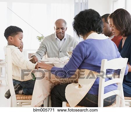 Stock Image - African American family praying before meal. Fotosearch