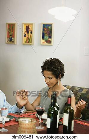 Stock Image - African American family saying grace at dinner table. Fotosearch