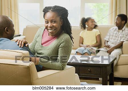 Picture - African American family sitting in living room. Fotosearch