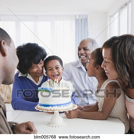 Stock Photo - African American family watching grandson blow out birthday candles. Fotosearch