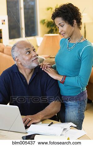Stock Photo - African American father paying bills while daughter looks on. Fotosearch