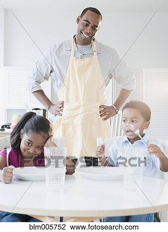 Stock Image - African American father preparing dinner for children. Fotosearch