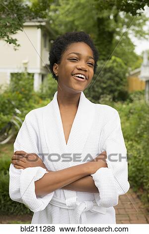 Stock Photo - African American girl wearing bathrobe in backyard. Fotosearch