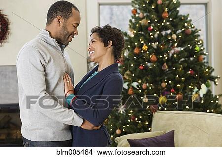 African American husband hugging wife by Christmas tree View Large Photo Image Picture - African American husband hugging wife by Christmas tree. Fotosearch