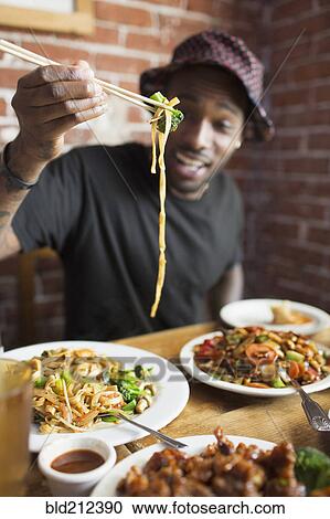 Stock Image - African American man eating at restaurant. Fotosearch