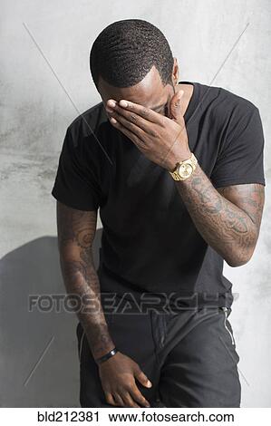 Stock Image - African American man holding his forehead. Fotosearch