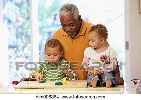 Picture - African American man making cookies with grandchildren. Fotosearch