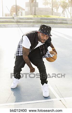 Stock Image - African American man playing on basketball court. Fotosearch