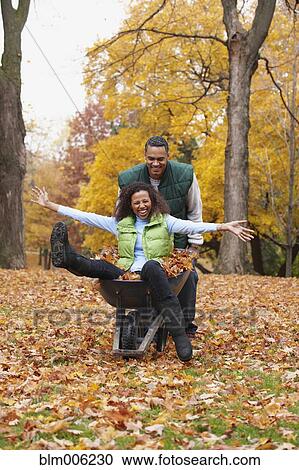 Stock Image - African American man pushing wife in wheelbarrow. Fotosearch