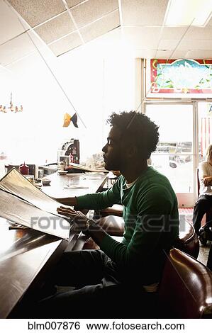 Stock Photograph - African American man reading menu at diner counter. Fotosearch