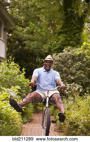 Stock Photo - African American man riding bicycle in backyard. Fotosearch