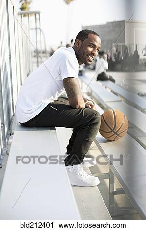 Stock Image - African American man sitting in bleachers. Fotosearch