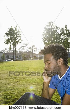 African American man sitting outdoors using cell phone View Large Photo Image Stock Image - African American man sitting outdoors using cell phone. Fotosearch