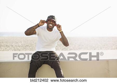 Stock Image - African American man smiling on beach wall. Fotosearch