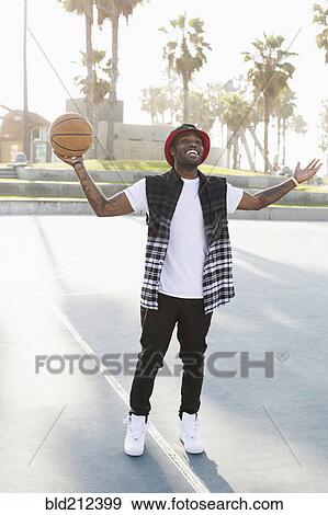 Stock Photo - African American man standing on basketball court. Fotosearch