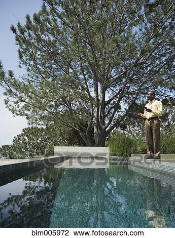 African American man text messaging on cell phone by swimming pool View Large Photo Image Stock Image - African American man text messaging on cell phone by swimming pool. Fotosearch