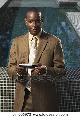 African American man text messaging on cell phone by swimming pool View Large Photo Image Stock Image - African American man text messaging on cell phone by swimming pool. Fotosearch