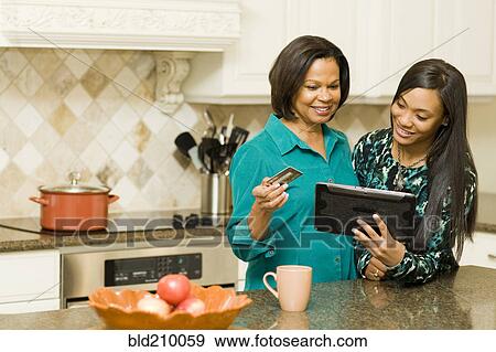 Stock Photo - African American mother and daughter using digital tablet. Fotosearch