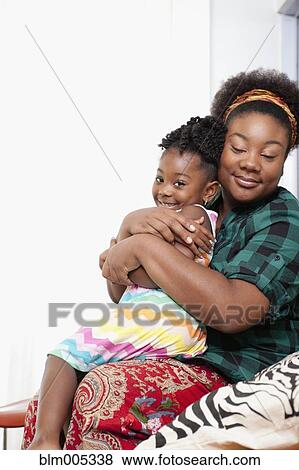 Stock Photo - African American mother holding daughter on lap. Fotosearch