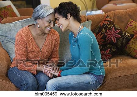 Stock Photo - African American mother talking with daughter in living room. Fotosearch
