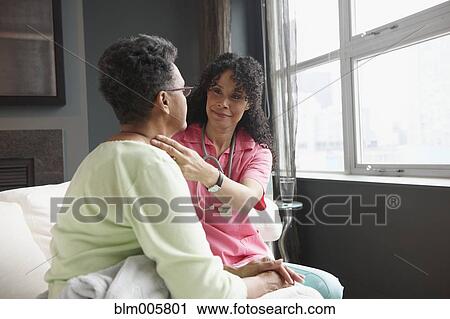 Stock Image - African American nurse checking on patient. Fotosearch