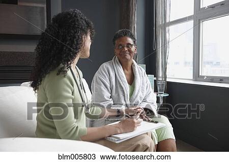 Stock Image - African American nurse checking on patient. Fotosearch
