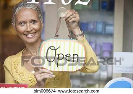 Picture - African American shop owner hanging open sign. Fotosearch
